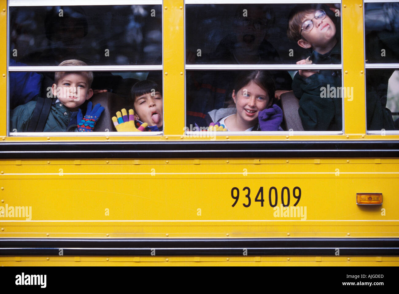 Young children making faces at the window as they ride in the school bus Stock Photo