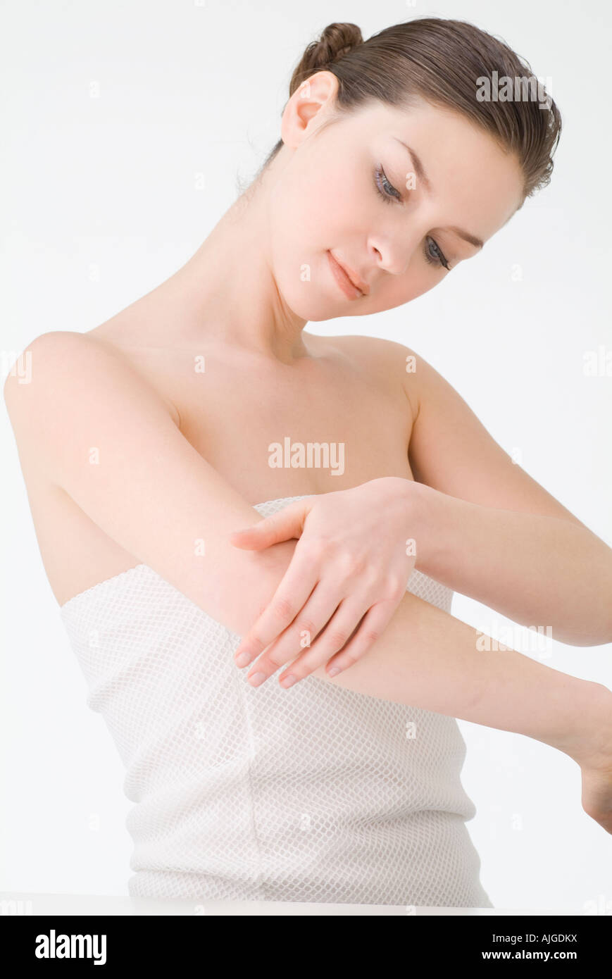 Young woman rubbing lotion on arm Stock Photo