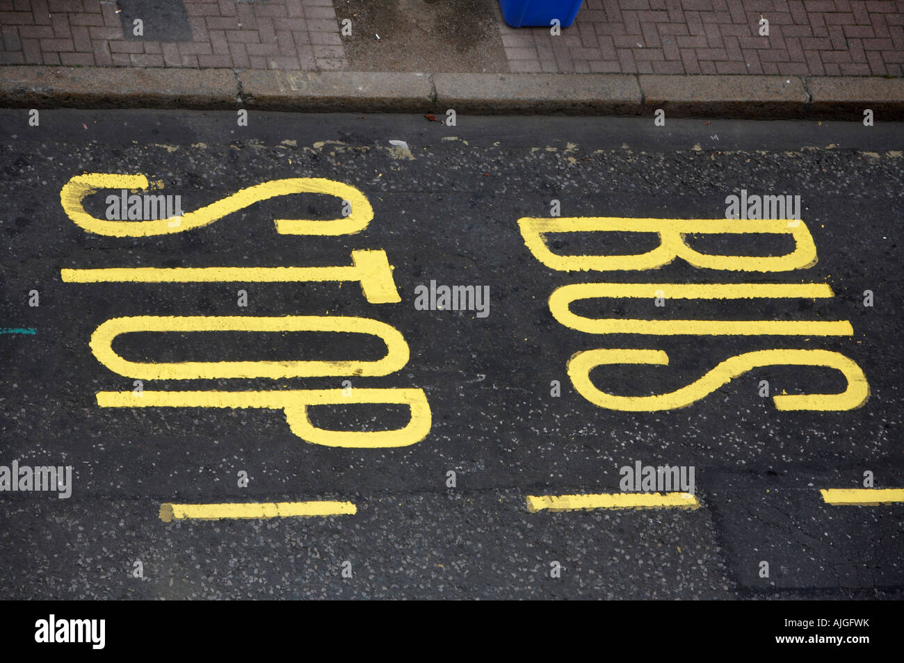 bus stop painted in bright yellow paint on tarmac at side of the road