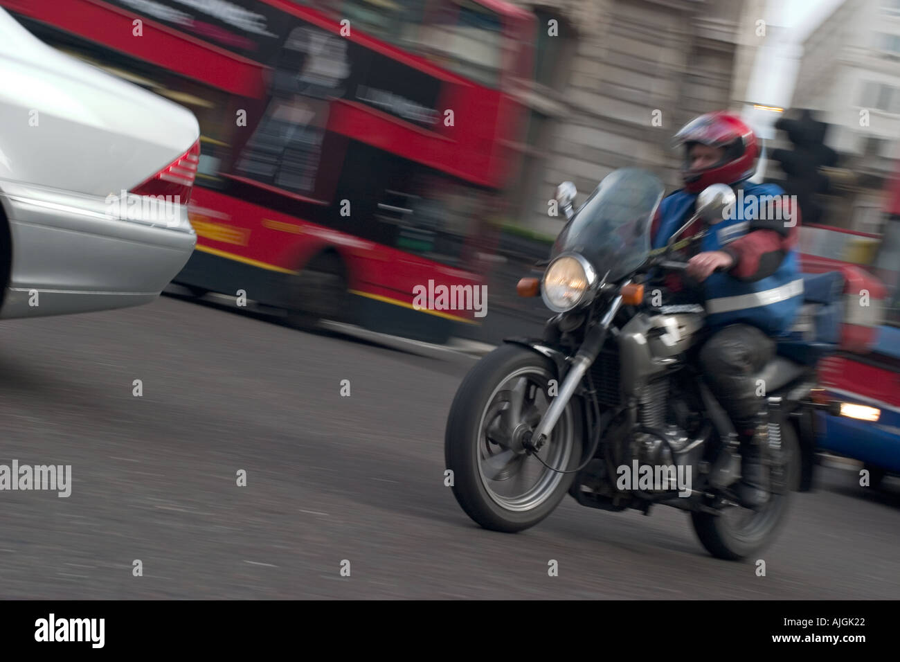 Motorcycle courier overtakes a car as he crosses Bank junction in the heart of Londons financial district Stock Photo