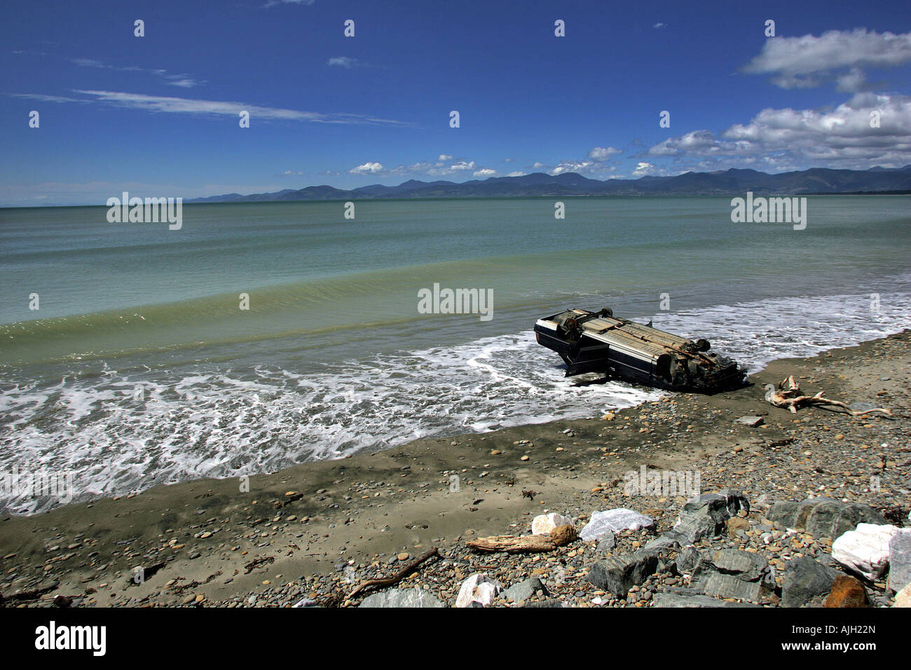 Car wreck upside down on scenic beach Ruby Bay Nelson New Zealand Stock Photo