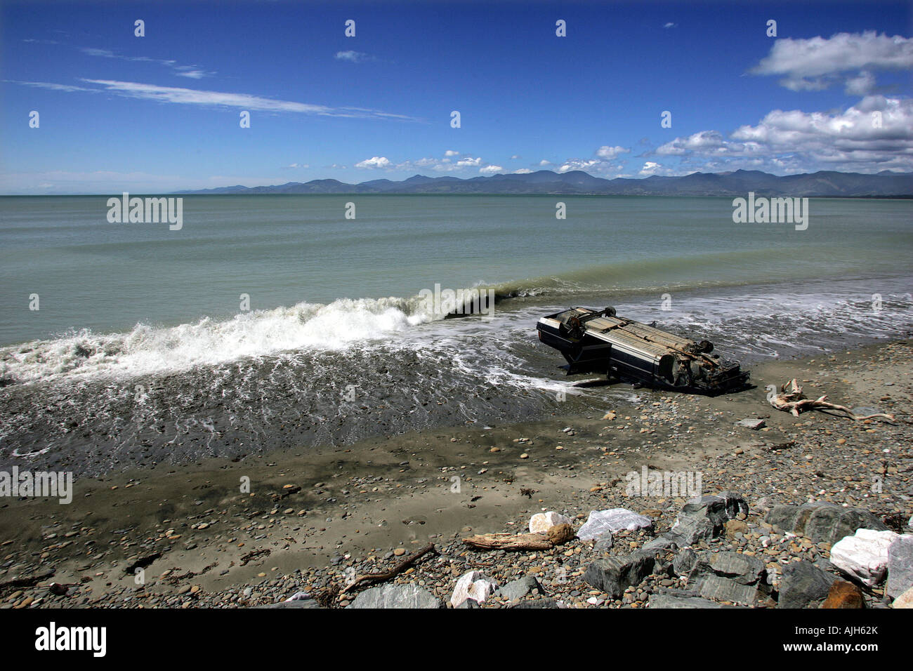 Car wreck upside down on scenic beach Ruby Bay Nelson New Zealand Stock Photo