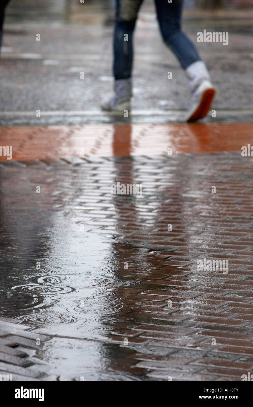 rain dripping drops into a puddle of water in pedestrian area of city
