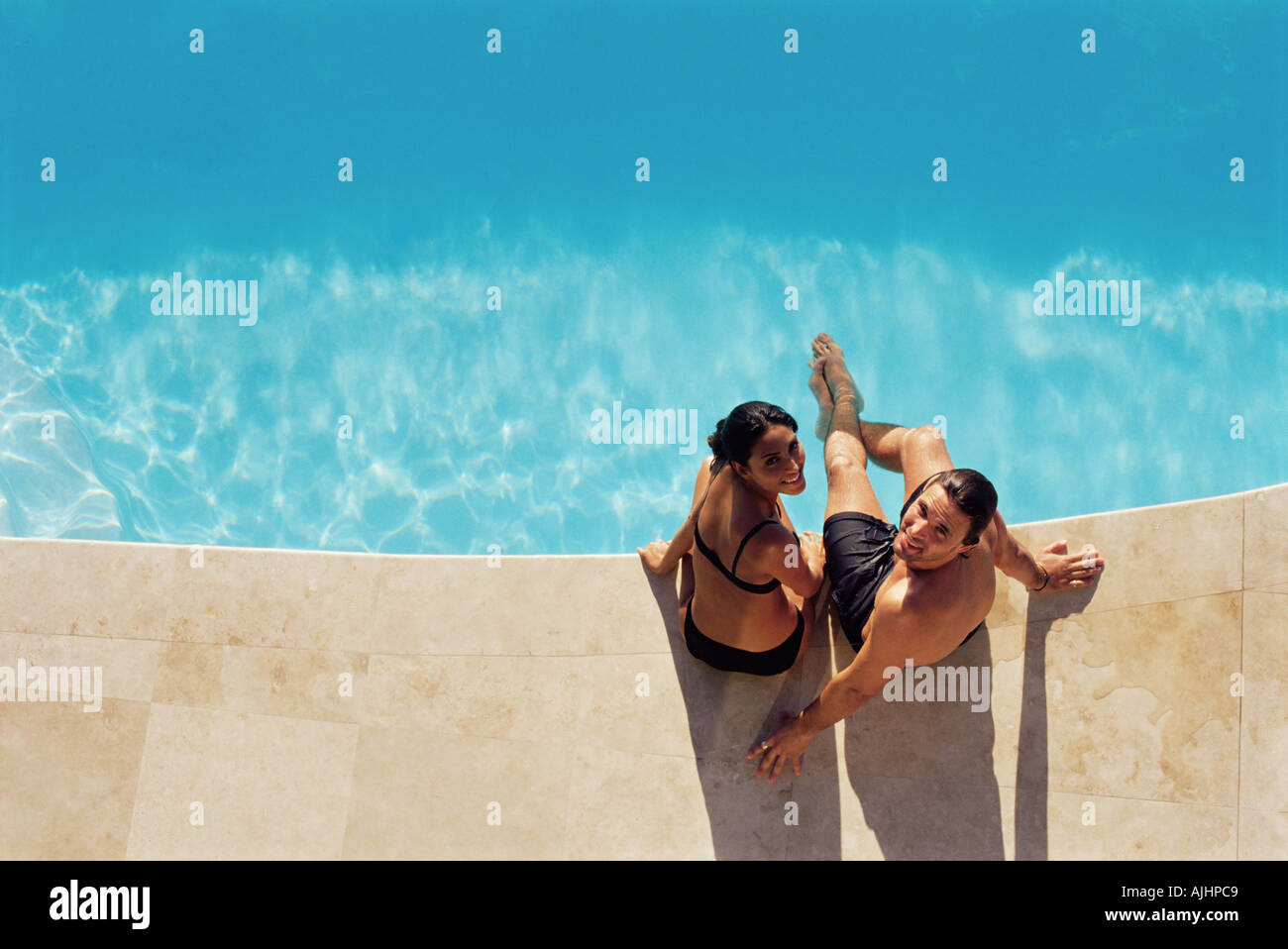 Couple sitting on the edge of swimming pool Stock Photo - Alamy