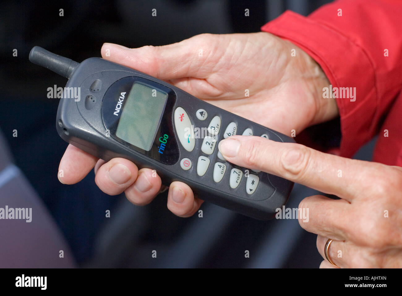 Close up of womans finger dialing on old Nokia mobile phone UK Stock Photo