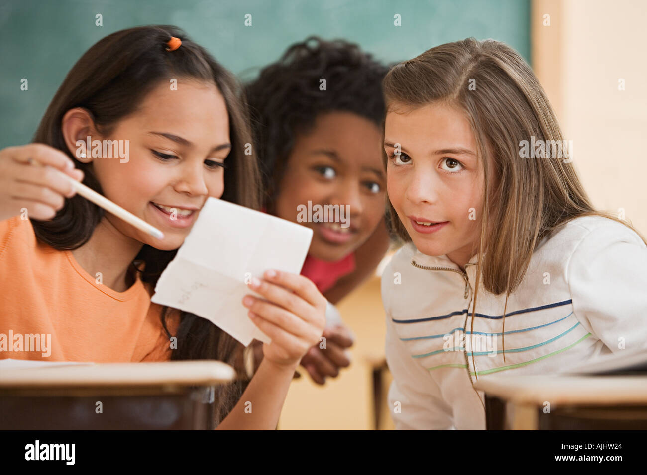 Three girls reading a note Stock Photo