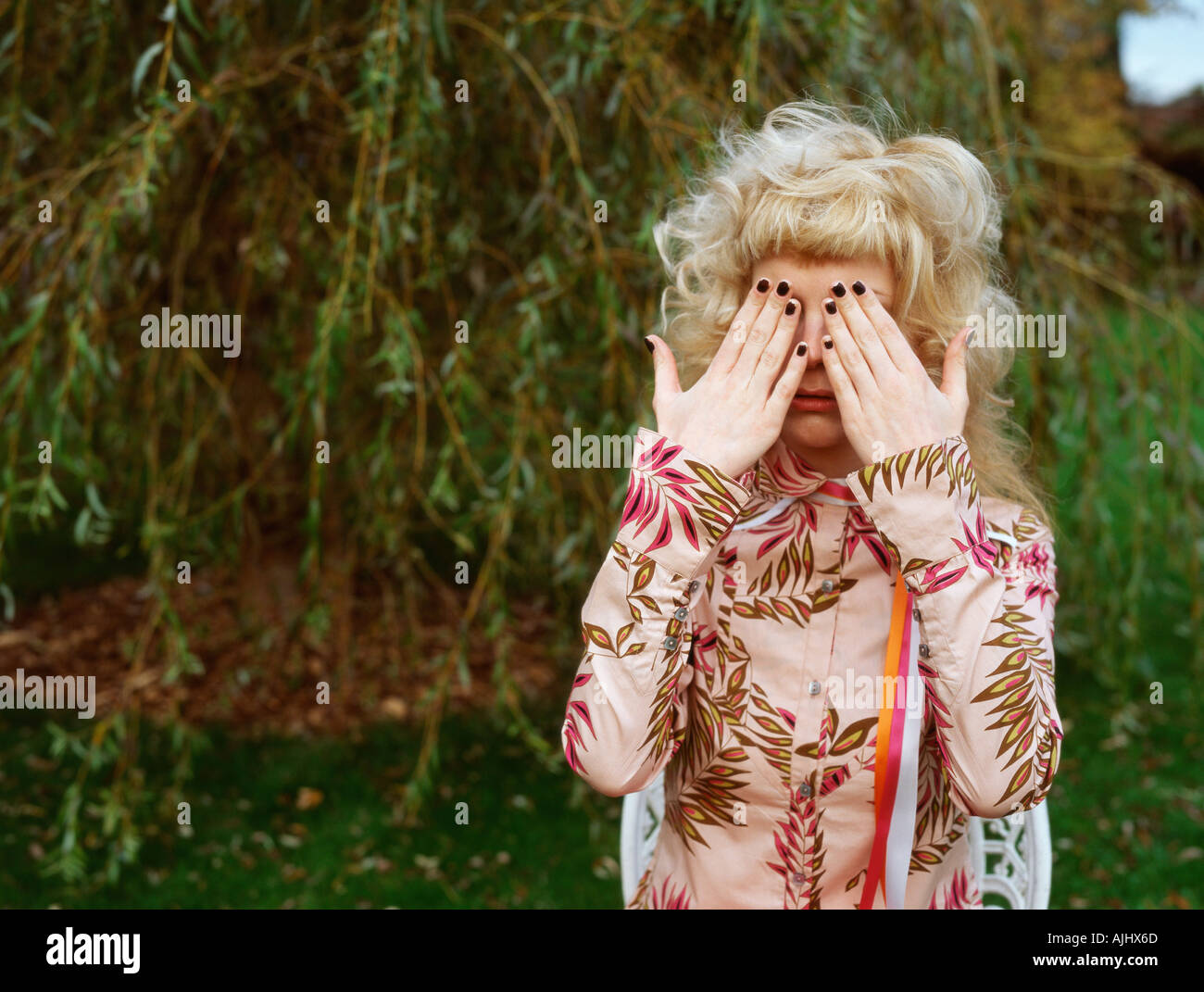 Woman in garden covering eyes Stock Photo