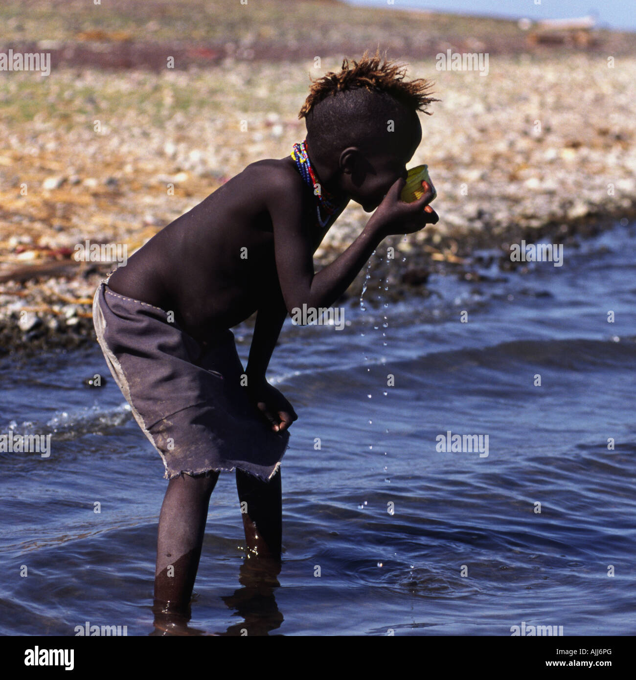 El Molo boy drinking the brackish water of lake Turkana. Kenya. Stock Photo