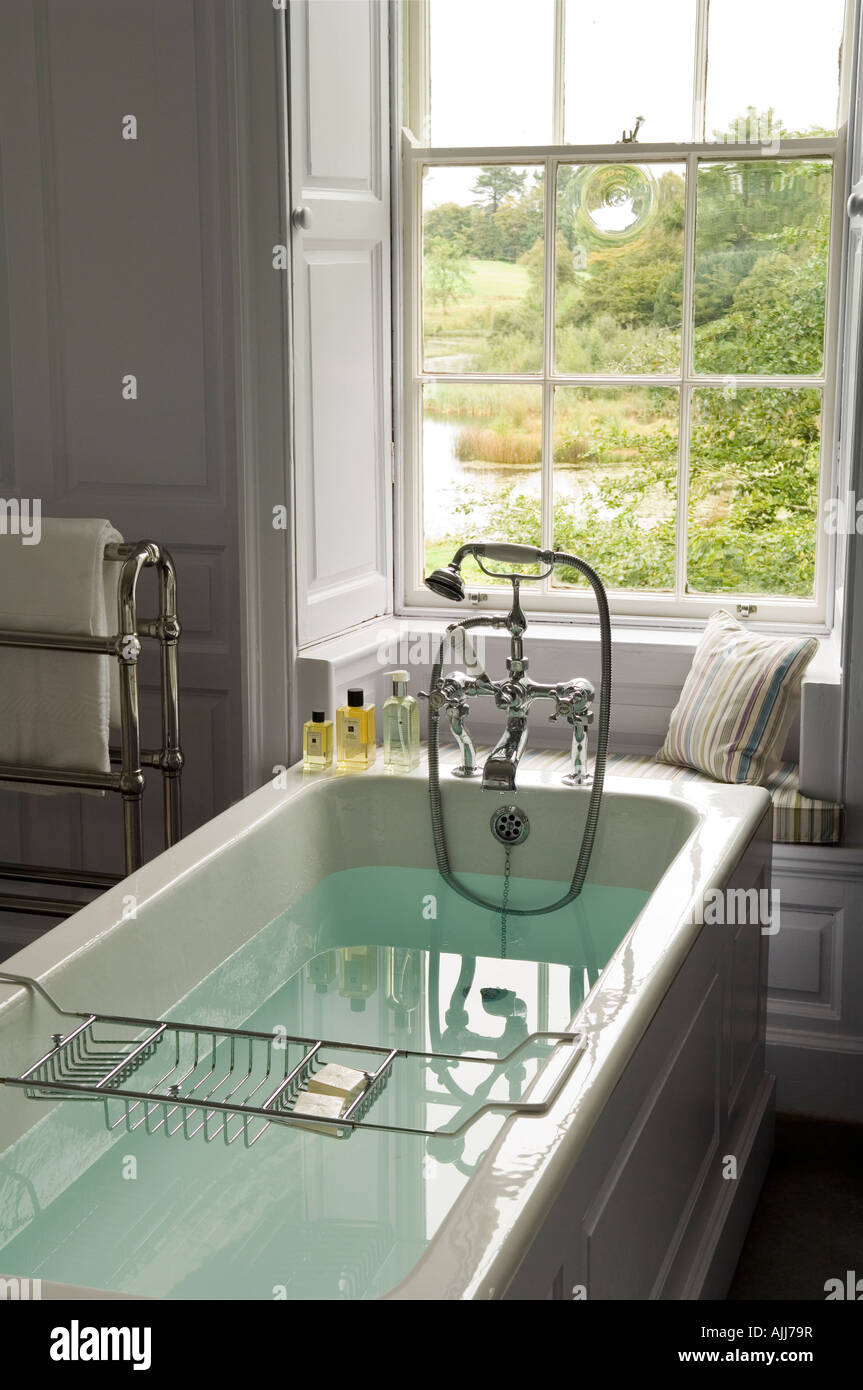 Filled bathtub with Edwardian bath shower mixer in bathroom of 18th