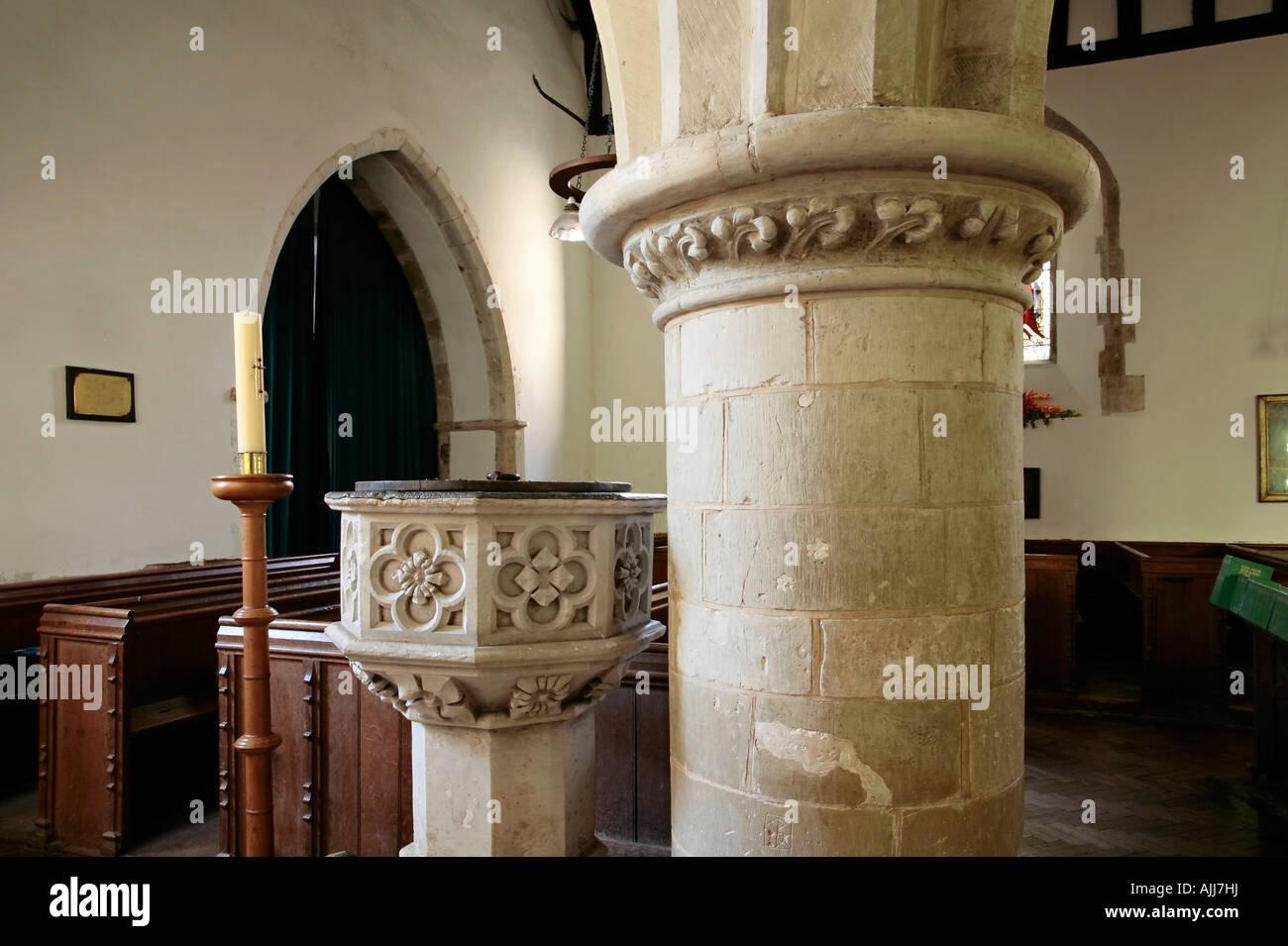 Paschal Candle beside Baptism font inside the church of St. John the Evangelist, Bury, West Sussex, UK Stock Photo
