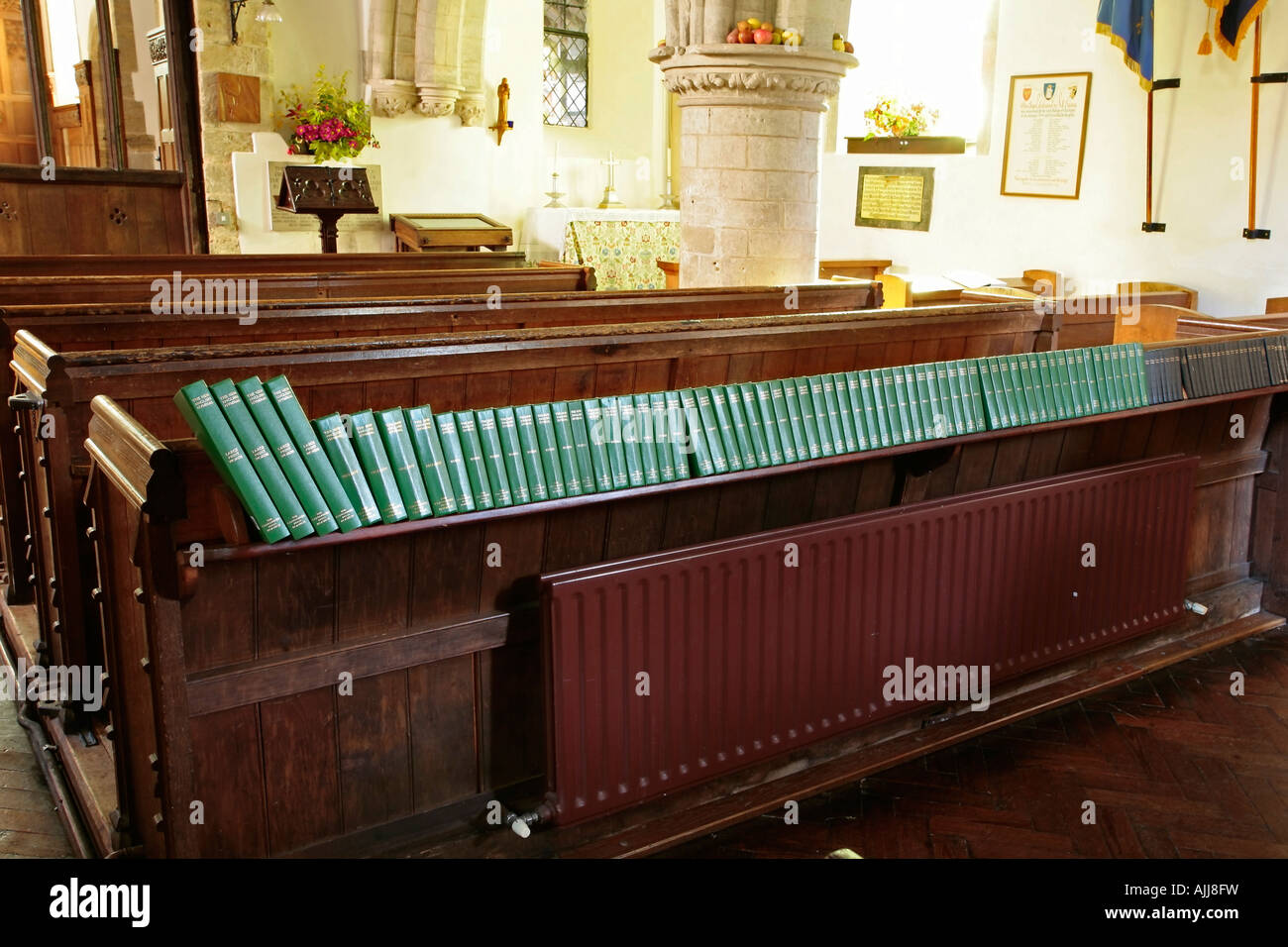 Row of hymn books on back of church pew. Church of St. John the Evangelist, Bury, West Sussex, England Stock Photo