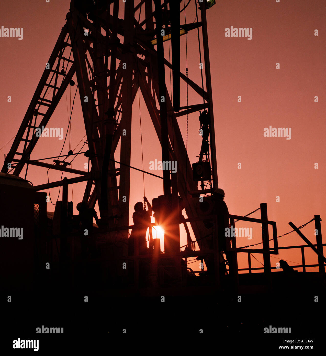 Oil field workers drill for oil at sunset Western Kansas Stock Photo