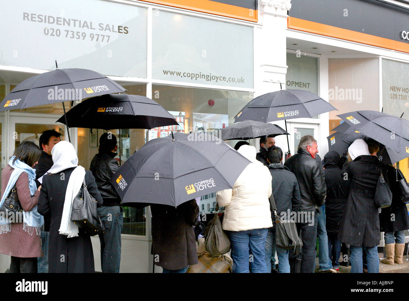 People queue in rain outside estate agents in London for release of batch of new homes for sale Stock Photo