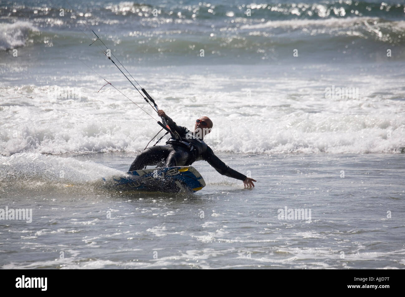 A man in a wetsuit parasurfs along a California beach. Stock Photo