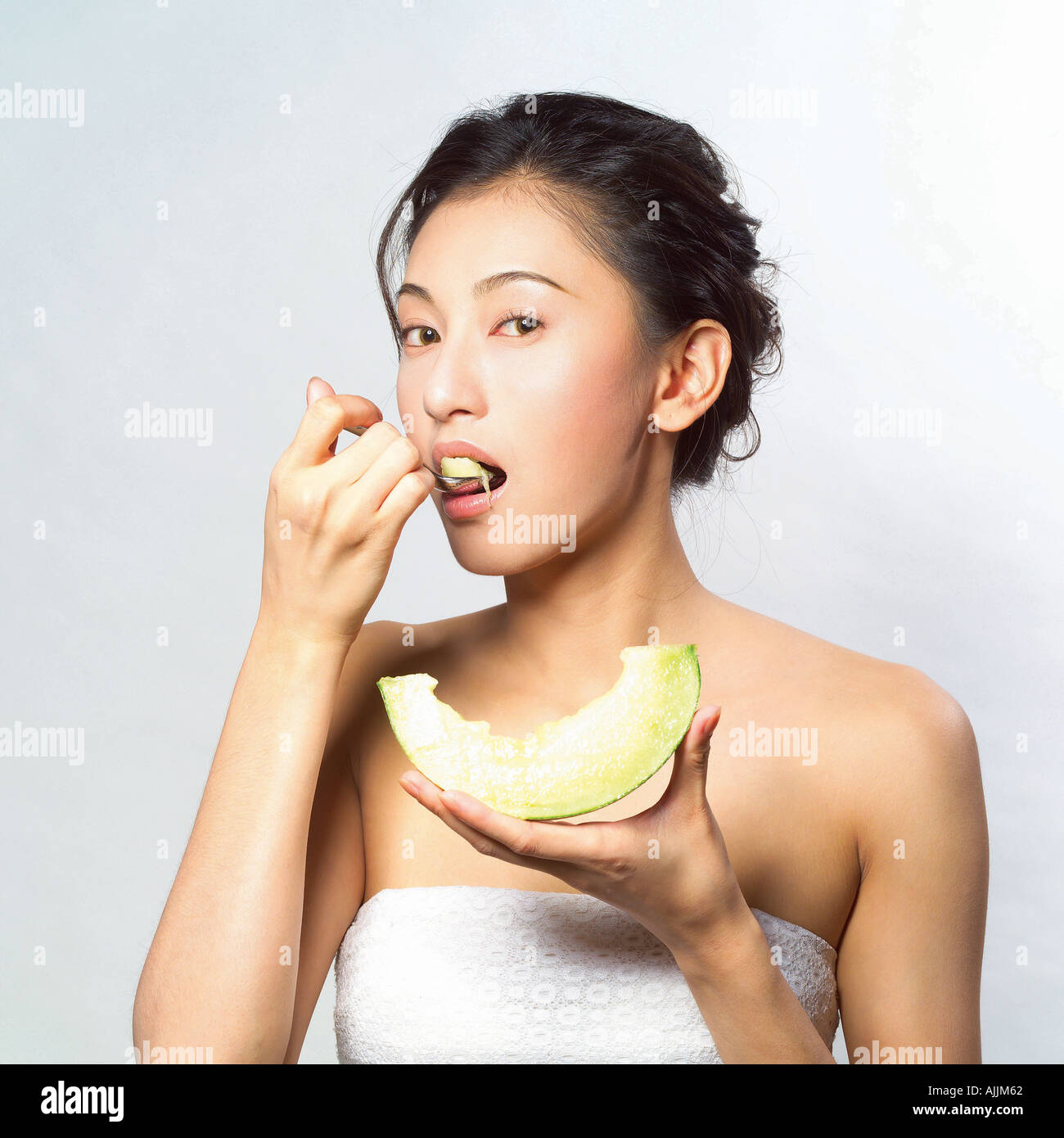 Young woman eating a melon slice with a spoon Stock Photo Alamy