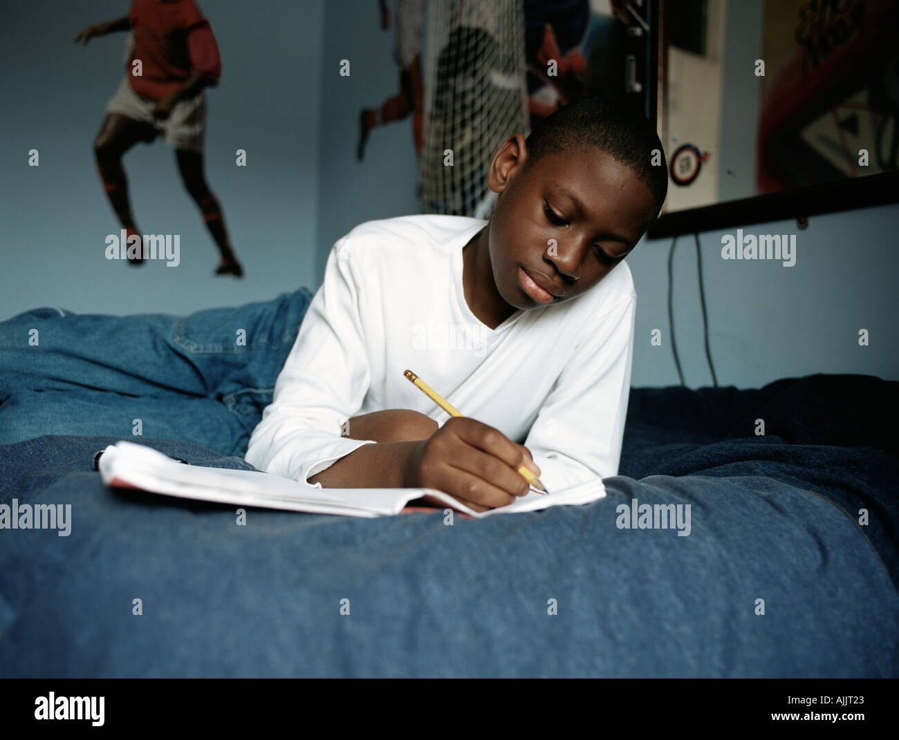 Boy doing homework on bed Stock Photo Alamy