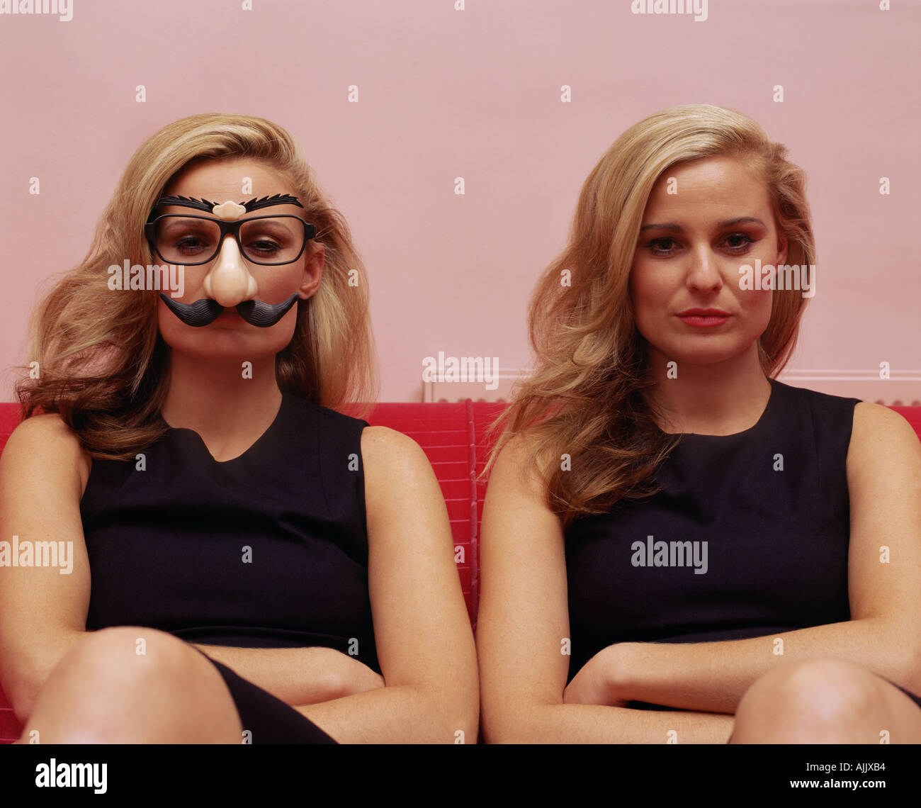 Two women one wearing a comedy disguise Stock Photo