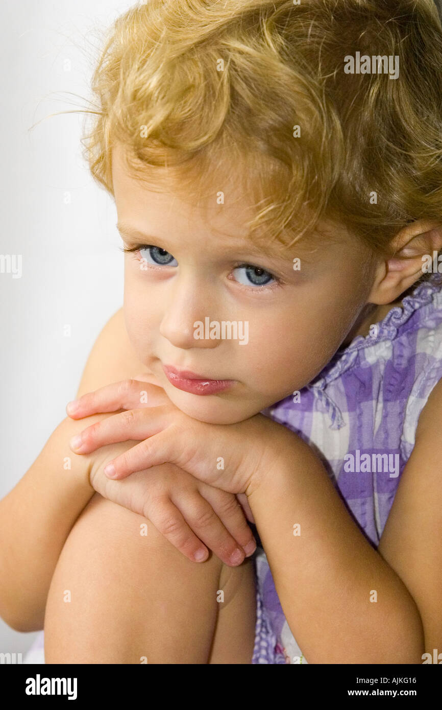 Child sitting with chin on knees Stock Photo Alamy
