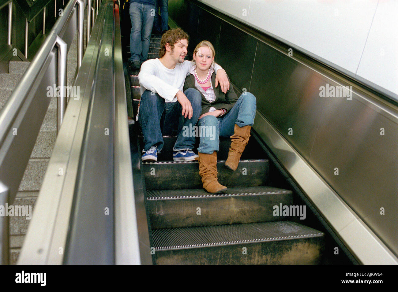 Couple sitting on escalator Stock Photo