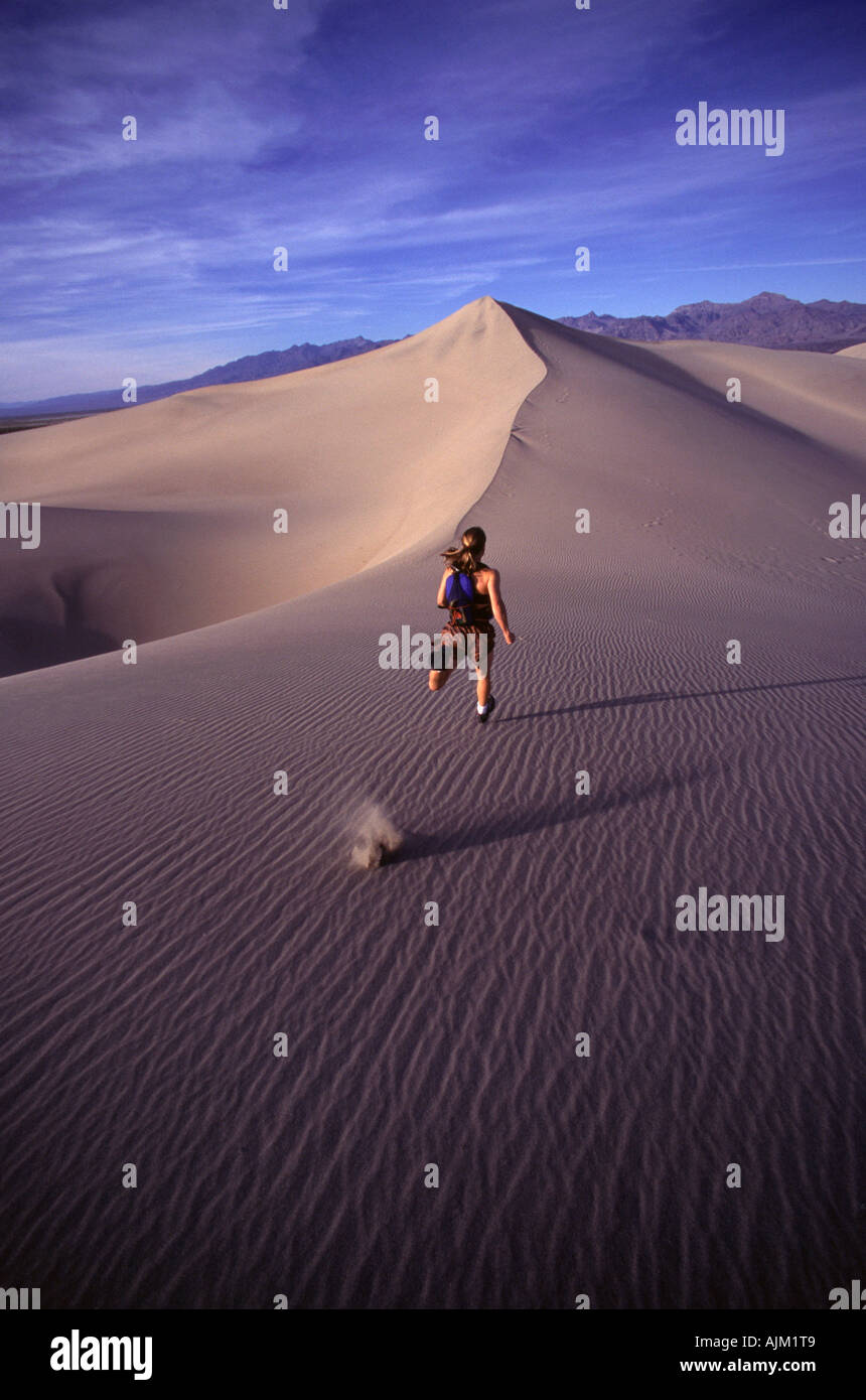 A woman running up a sand dune in Death Valey CA Stock Photo