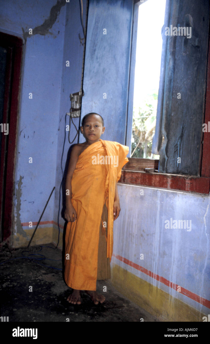 A novice monk stands in a gently decaying temple in Champasak southern Laos Stock Photo