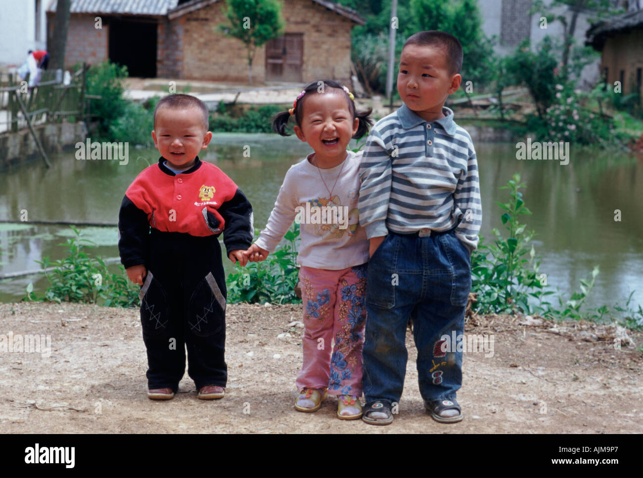 Three young Chinese children at a farmhouse fishing pond Xiangtan Hunan China Stock Photo