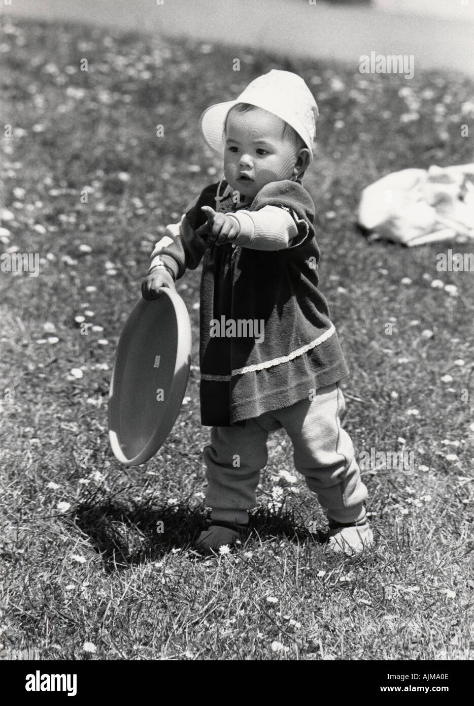 5318 18 fourteen month old girl pointing as she holds frisbee in a park San Francisco California USA Stock Photo