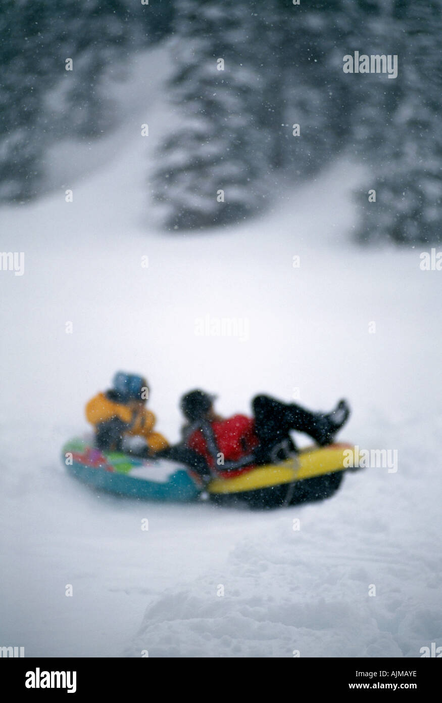 Mother daughter tubing through fresh snow Rocky Mtns CO Stock Photo