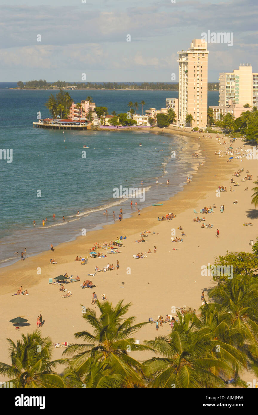 San Juan Puerto Rico Isla Verde beach with sunbathers, blue sky and resort hotels in background, plam trees lining beach, aerial Stock Photo