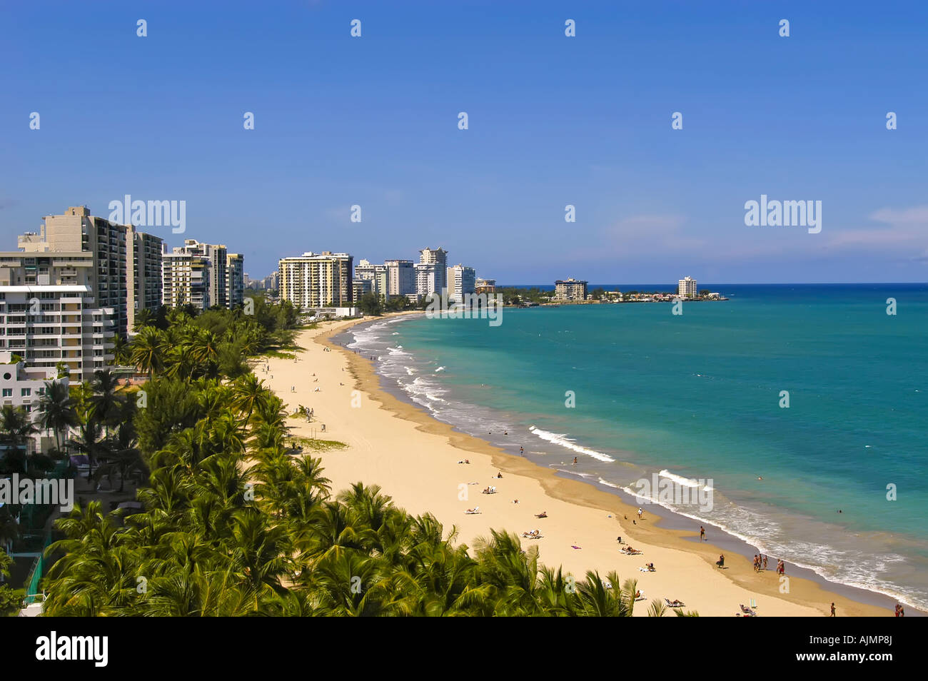 San Juan Puerto Rico Isla Verde beach with sunbathers, blue sky and resort hotels in background, plam trees lining beach, aerial Stock Photo