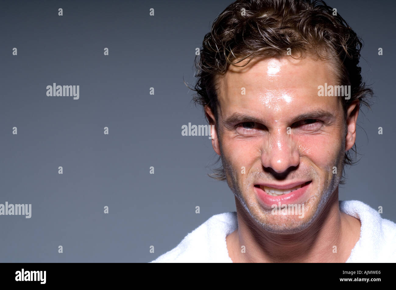 young man wearing bathrobe making funny faces with transparent face mask Stock Photo