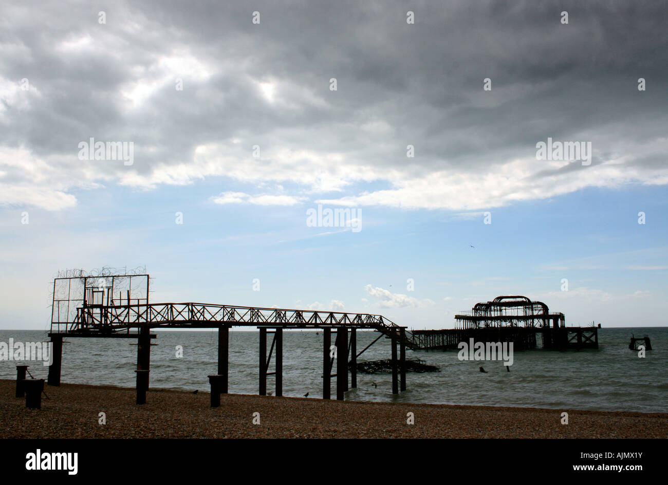 Dark storm clouds above remains of west pier destroyed by fire on Brighton seafront, England, UK Stock Photo