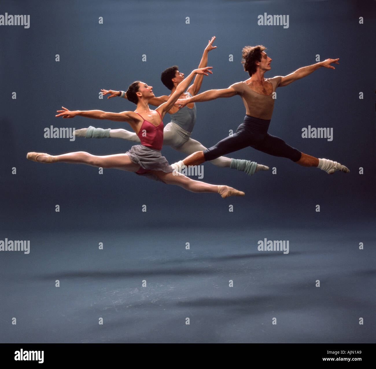 Three ballet dancers execute a grand jete in a studio Stock Photo