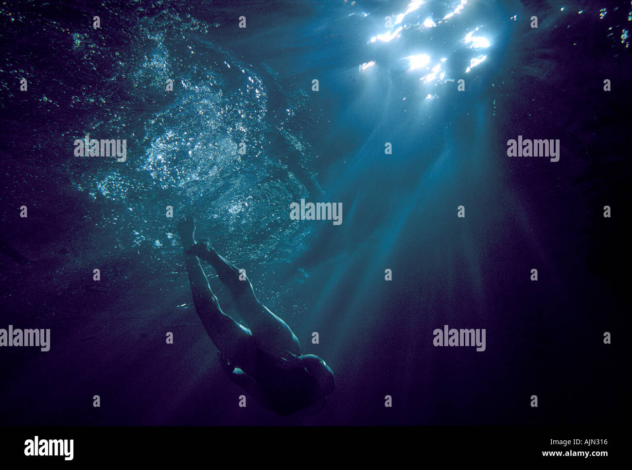 woman swimming underwater in moonlight Stock Photo
