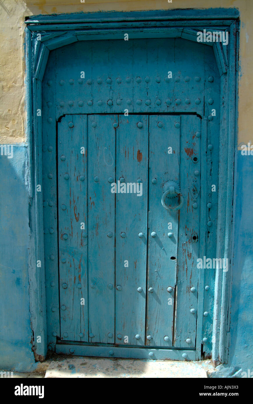 An old wooden door with flaking sky blue paint in the Kasbah in Tangiers, Morocco Stock Photo