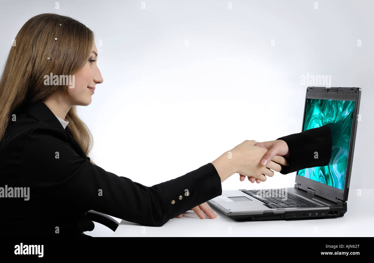 Attractive young businesswoman shaking hands with her partner virtually over the Internet Stock Photo