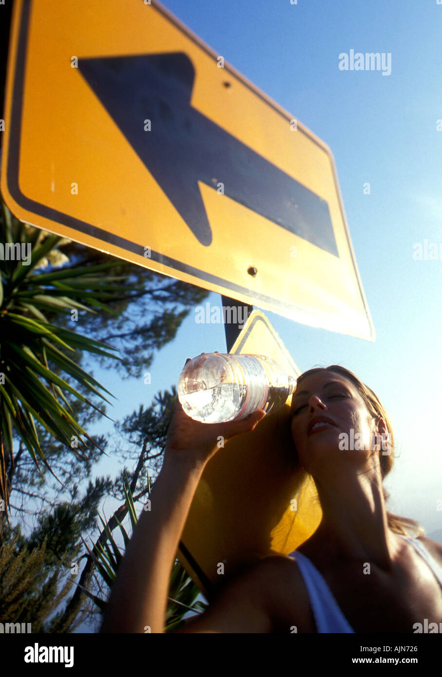 WOMAN JOGGER DRINKING BY ROADSIGN Stock Photo