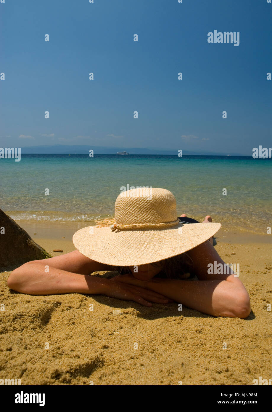 woman female wearing straw hat lying on sandy beach with blue ...
