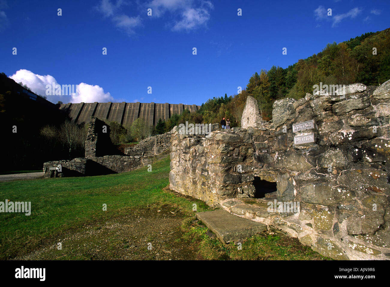 The Clywedog Dam towers above the preserved ruins of the Bryntail lead mine. Stock Photo