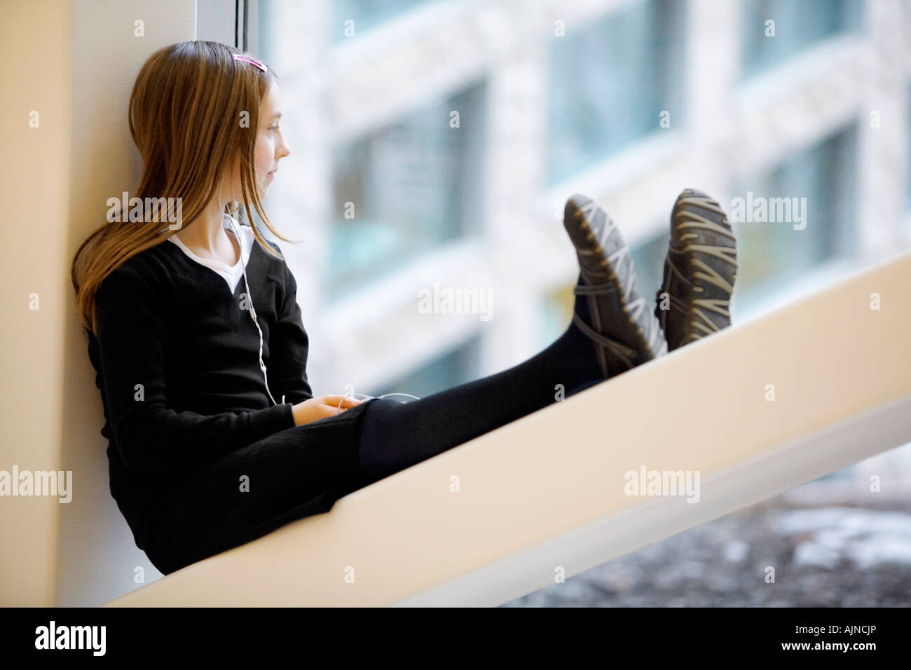 Girl sitting on windowsill listening to music Stock Photo - Alamy