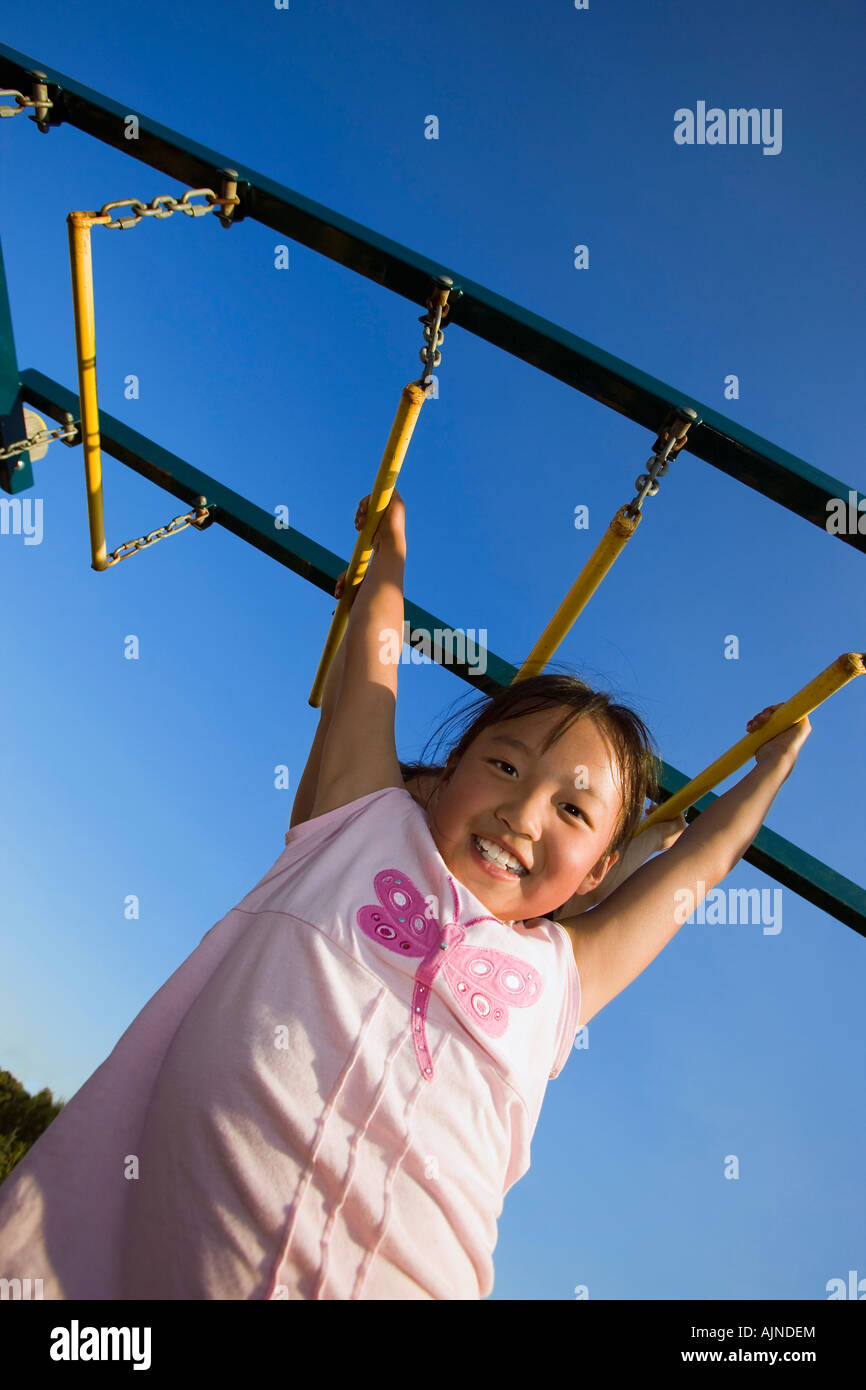 A young girl hanging from bar Stock Photo