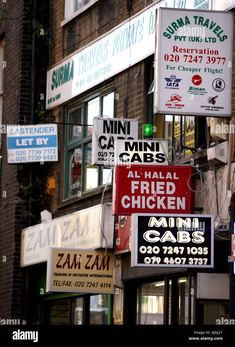 Signs for Curry Houses Fast Food Travel Companies and Mini Cabs hang in Brick Lane East London United Kingdom Stock Photo