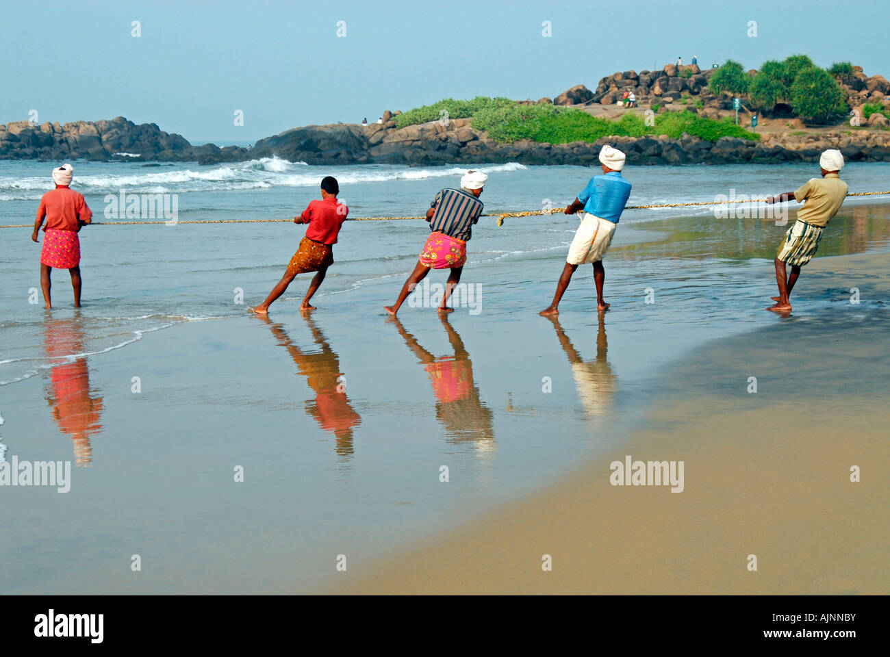 Catching Fish With Rope Fishermen holding rope to take out fishing net from the sea with fish ...