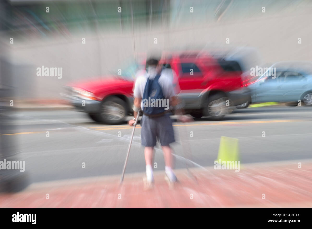 Man on crutches wearing a backpack waiting to cross a busy city street