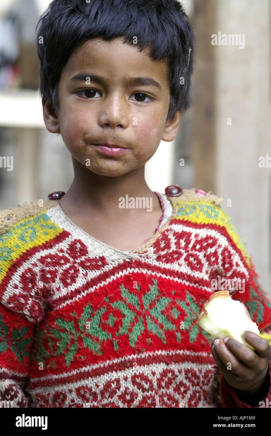 Young indian boy child kid eating apple fruit outdoors. India. Stock Photo