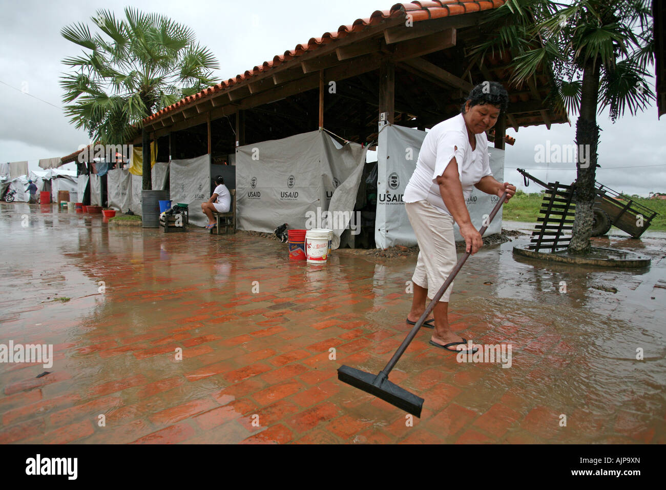 Woman sweeps away water in a camp set up by US Aid, after being made homeless by serious flooding in the Beni region of Bolivia Stock Photo