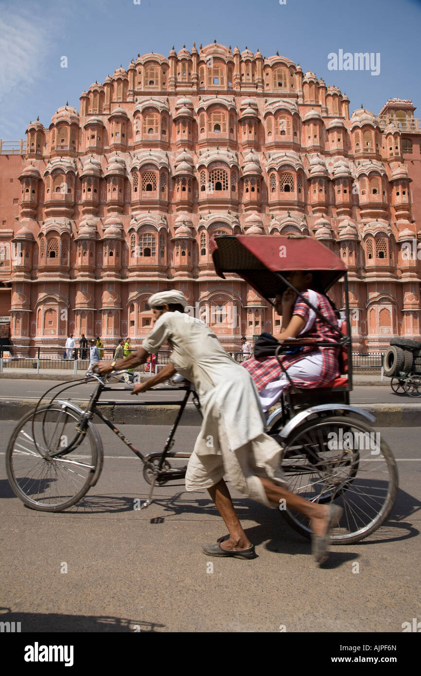 Cycle rickshaw driver pushes passengers along street in front of the Palace of the Winds in Jaipur, Rajasthan, India Stock Photo