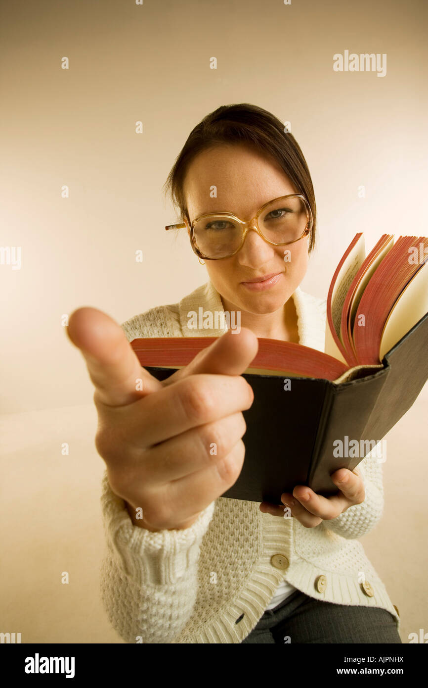 A woman holding book and pointing to the camera Stock Photo