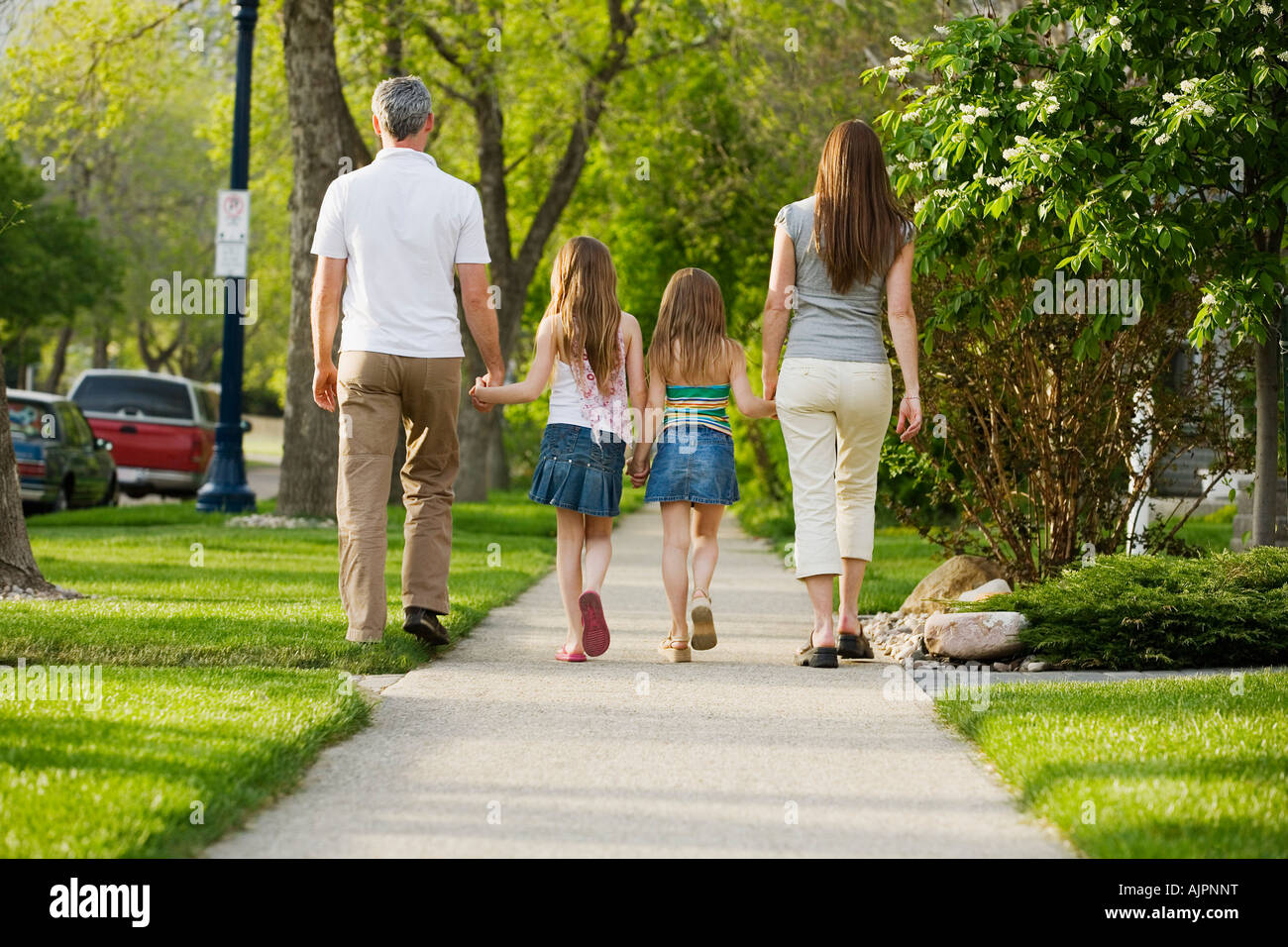 Rear view of family walking on sidewalk Stock Photo