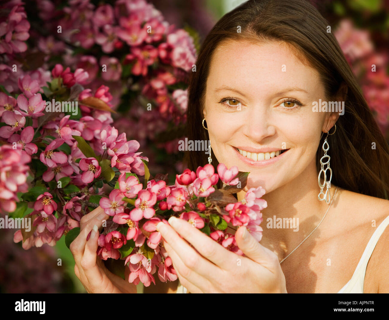 Young woman smiling and smelling flowers Stock Photo - Alamy